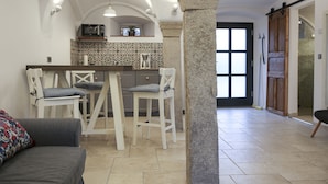 A kitchen with a bar area, white chairs, and a stone column. - Live like in a castle, in the vaulted room, rental after complete renovation (Grafengehaig)