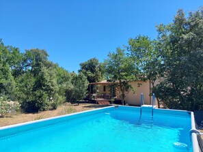 A swimming pool with a sun deck area, surrounded by trees and a building. - Detached villa, swimming pool, spa, patio furniture. Near Vallon Pont d'Arc. (Labastide-de-Virac)