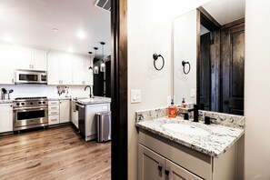 A modern kitchen with stainless steel appliances, a granite countertop, and wooden flooring.