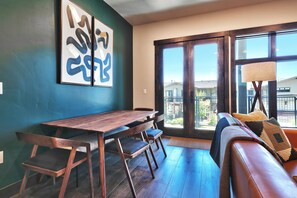 Ein modernes Wohnzimmer mit einem Holzesstisch, einer Couch und einem großen Fenster mit Blick nach draußen.
