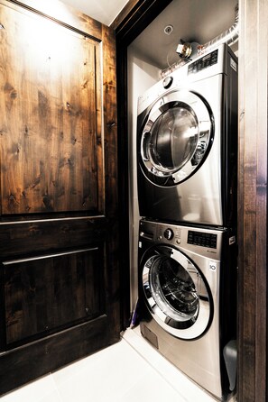 A compact laundry room with a built-in washer and dryer, wooden cabinetry, and a tiled floor.