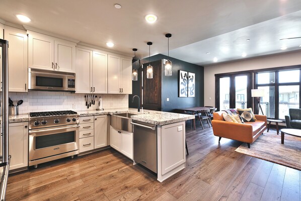 A modern kitchen with stainless steel appliances, a central island, and a dining area with a sofa and table.