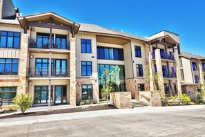A multi-story residential building with balconies, large windows, and a stone facade.