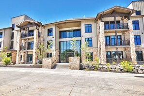 A multi-story building with a stone facade, large windows, and a flat roof.
