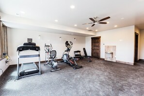 A home gym with exercise equipment, a ceiling fan, and a water dispenser.