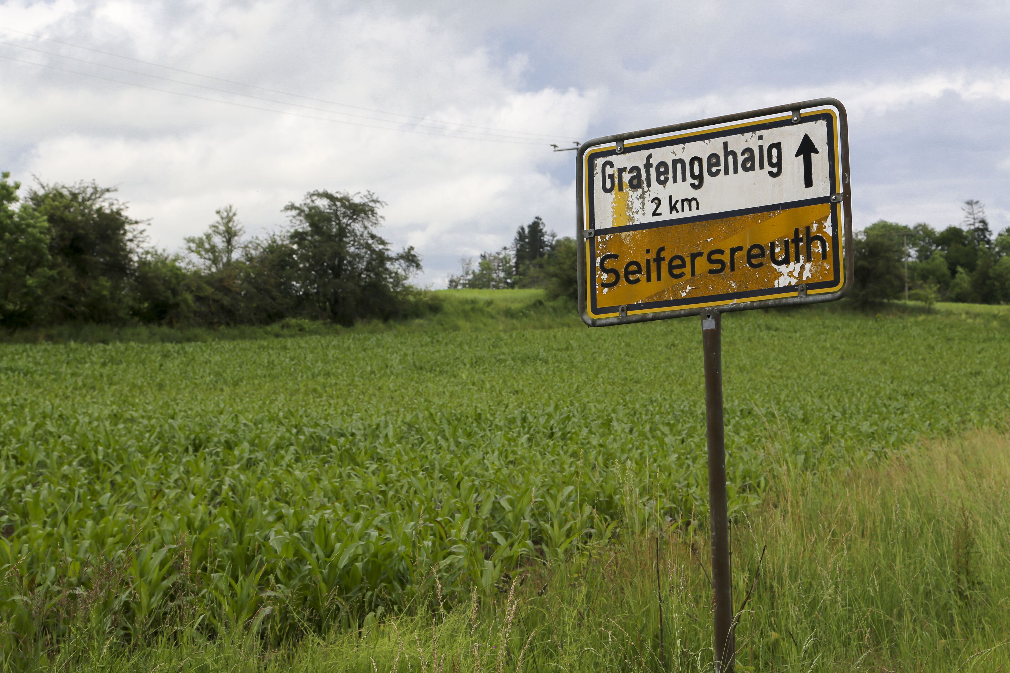 Een richtingsbord in een landelijke omgeving, met een veld op de achtergrond.