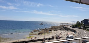 A coastal view with a beach, rocky shoreline, and a road curving along the coast. - Beautiful apartment with a balcony and ocean view in the center of Concarneau (Concarneau)