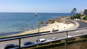 Une route côtière, avec une plage sur la droite, un ciel dégagé et une vue sur la mer.