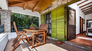 An outdoor patio with a wooden table and chairs, a stone wall, and a green door. - House 2041/31790 (Istria - Rovinj), 1000m from the beach (Rovinj)