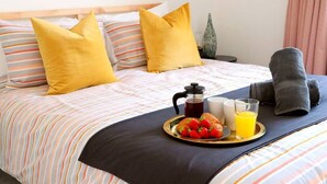 A neatly made bed with striped bedding, a tray with strawberries and orange juice, and a bottle of water. - NEW Poole House 5 mins to Sandbanks +Netflix (Poole)
