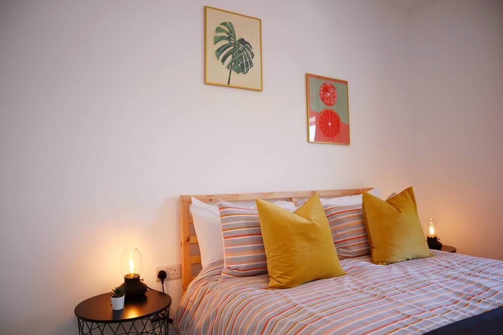 Una camera da letto con un letto, cuscini, un comodino con una lampada e decorazioni a parete.