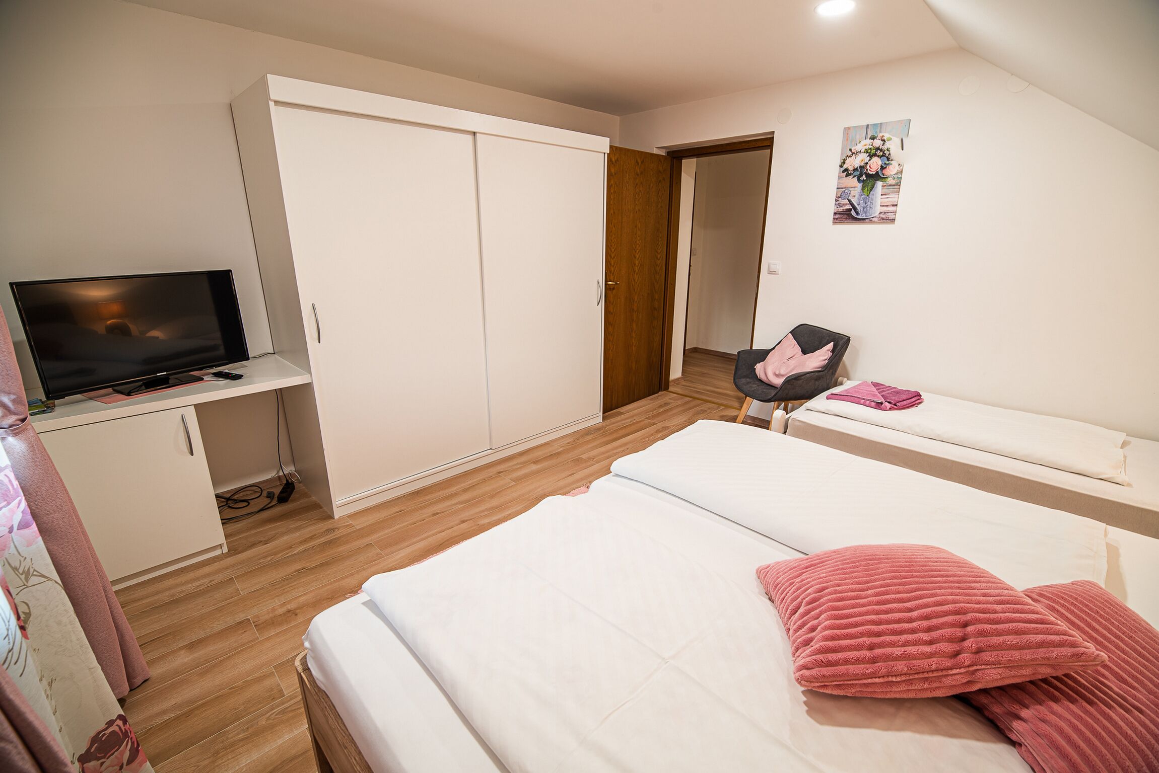 Ein Schlafzimmer mit Bett, Fernseher, Kleiderschrank und Schreibtisch.