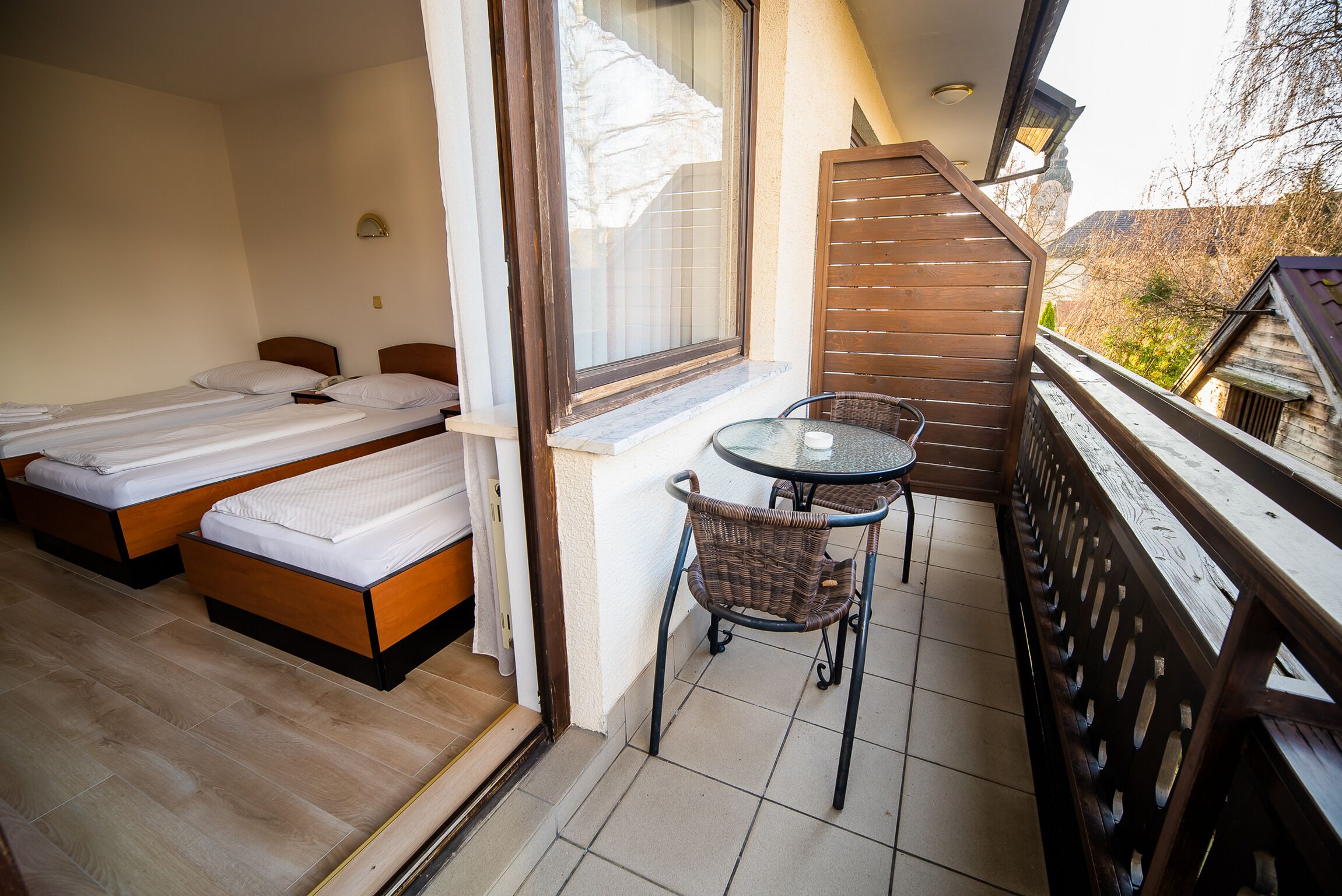 A balcony with two beds, a table, and chairs.