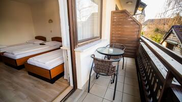 A balcony with two beds, a table, and chairs.