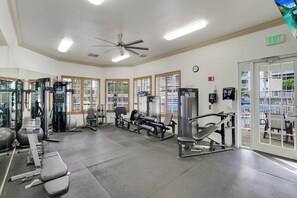 A gym with various exercise equipment, large windows, and an exit sign. - Regatta - William Raveis Rentals (Naples)