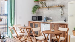 A compact kitchen with a wooden table and chairs, a microwave, and a sink. - A Calata (Noto)