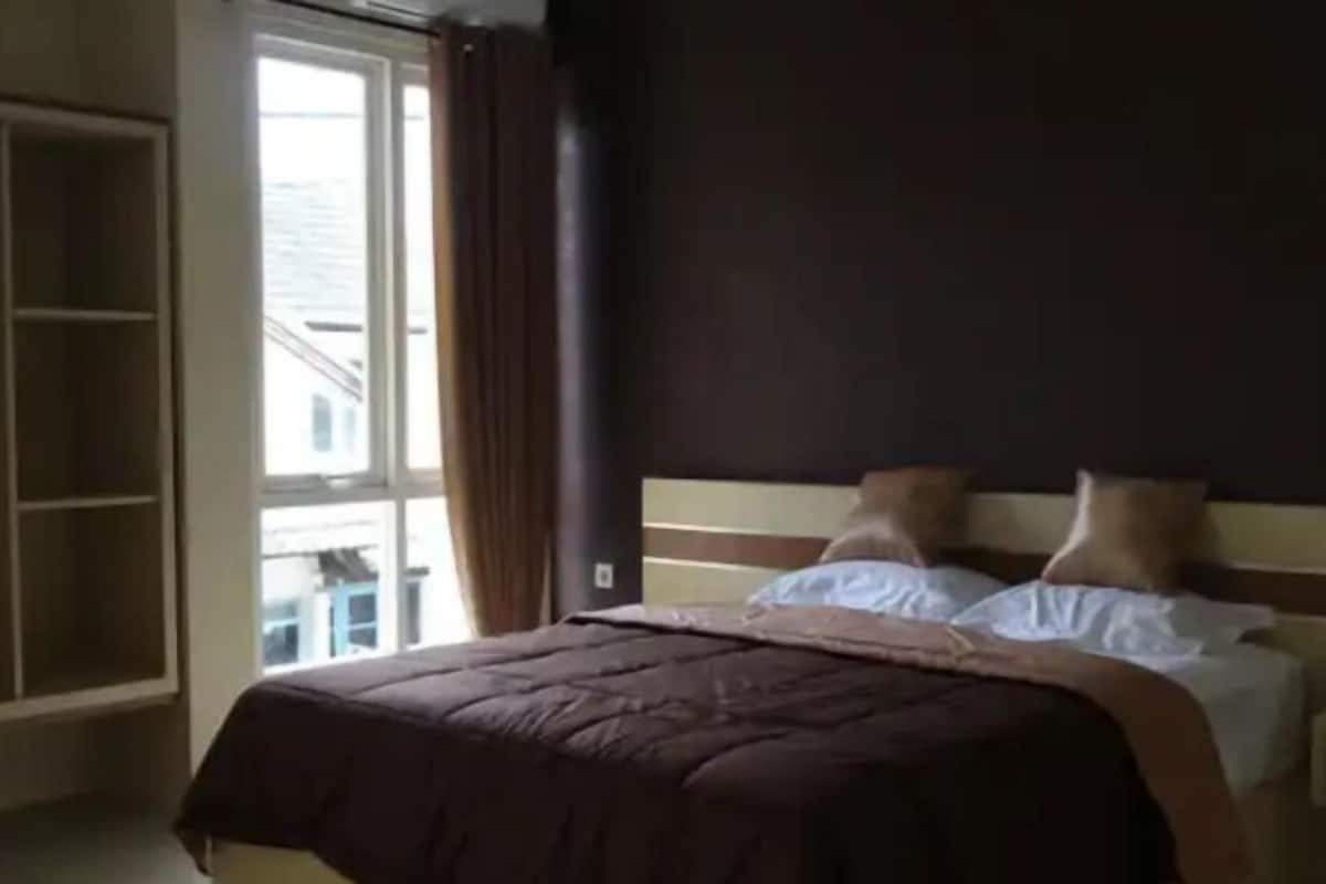 A bedroom with a bed, a nightstand, a wardrobe, and a window.