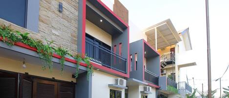 A modern multi-story residential building with balconies, air conditioning units, and a mix of stone and plaster exterior walls.