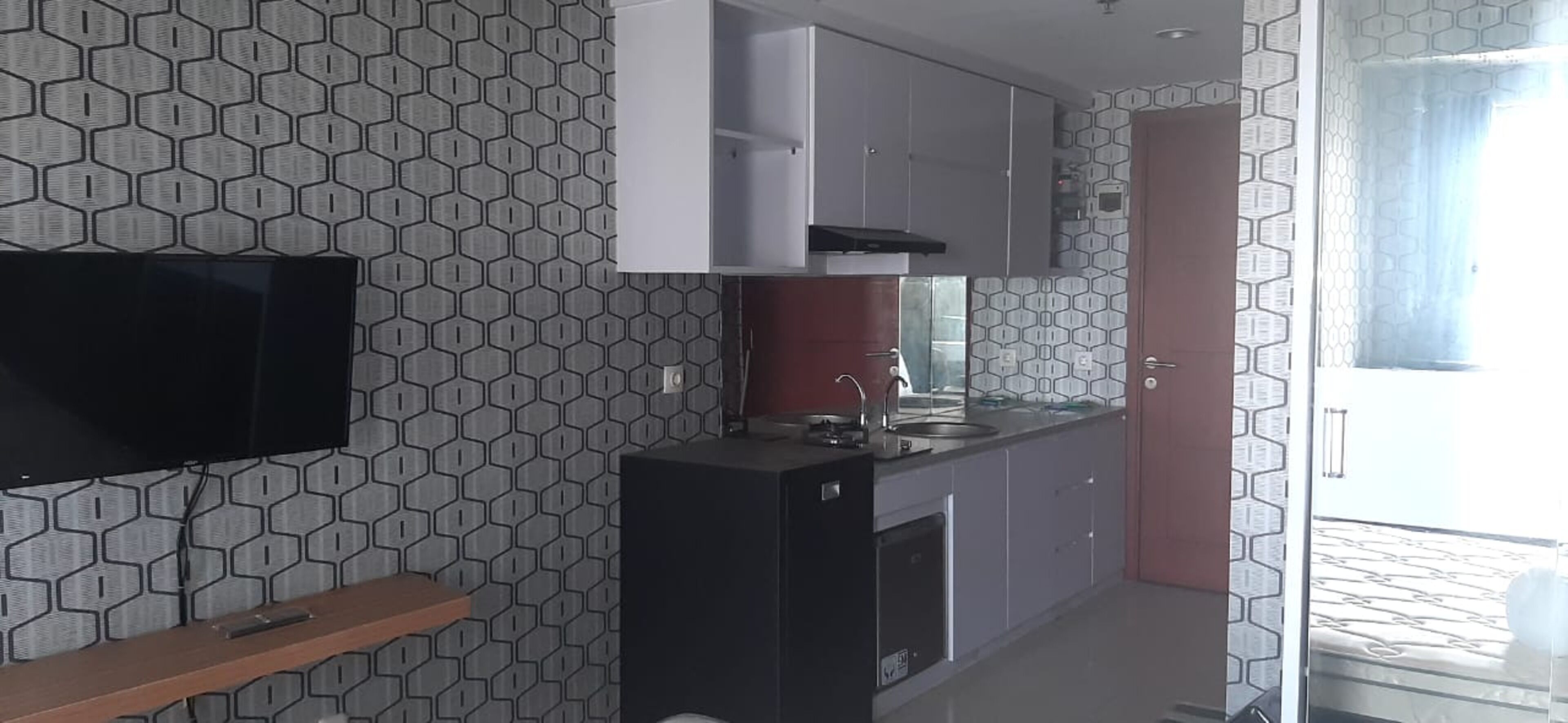 Una cocina compacta con televisor integrado, microondas y lavamanos.