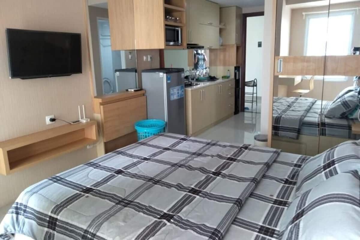 Une chambre comprenant un lit, une télévision et une kitchenette équipée d’un four à micro-ondes, d’un réfrigérateur et d’un évier.