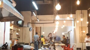 A restaurant interior with a bar area, wooden tables, and hanging light bulbs. - Mahogany x Sagita Karawang by Zuzu (Karawang)