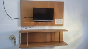 A television mounted on a wooden panel with a shelf below.