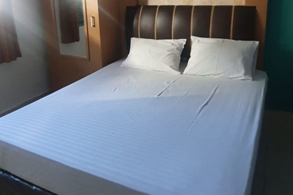Un lit bien fait, avec une tête de lit, un miroir et un mur décoré d’un motif.
