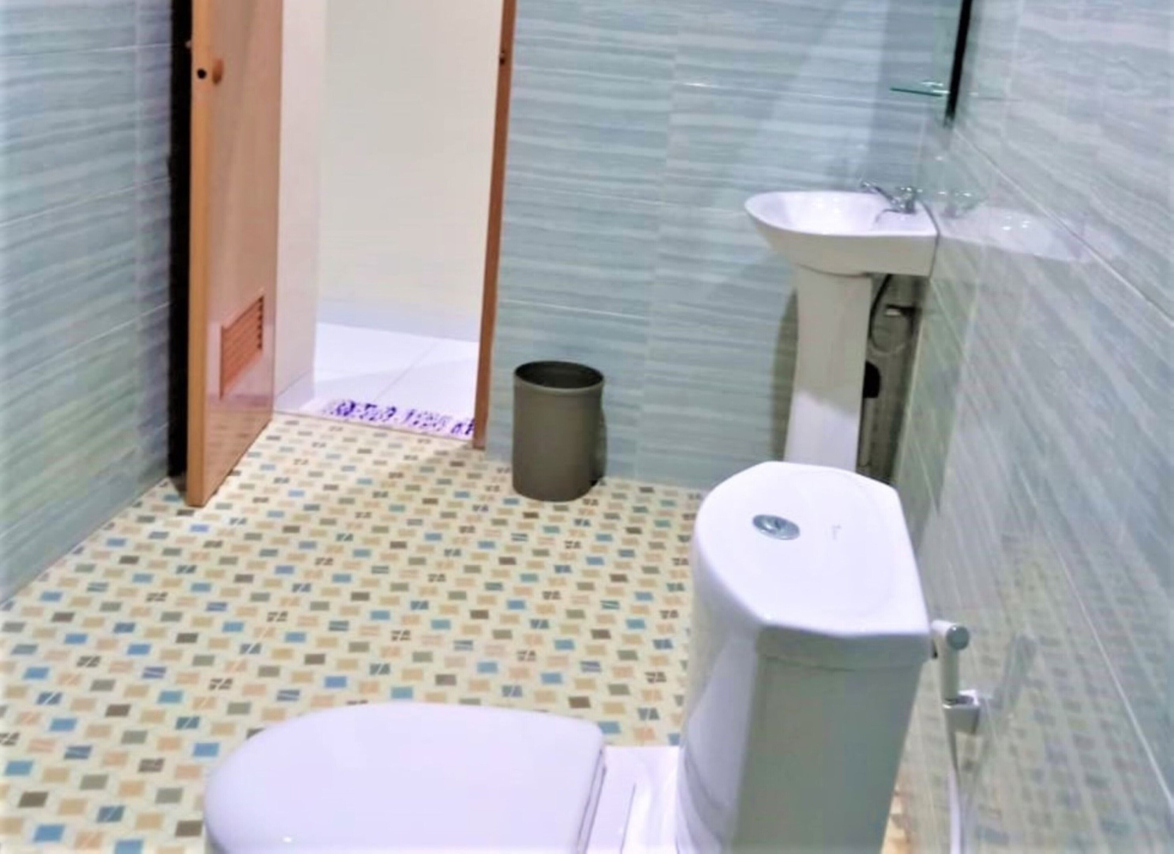 A small bathroom with a toilet, sink, and trash can.