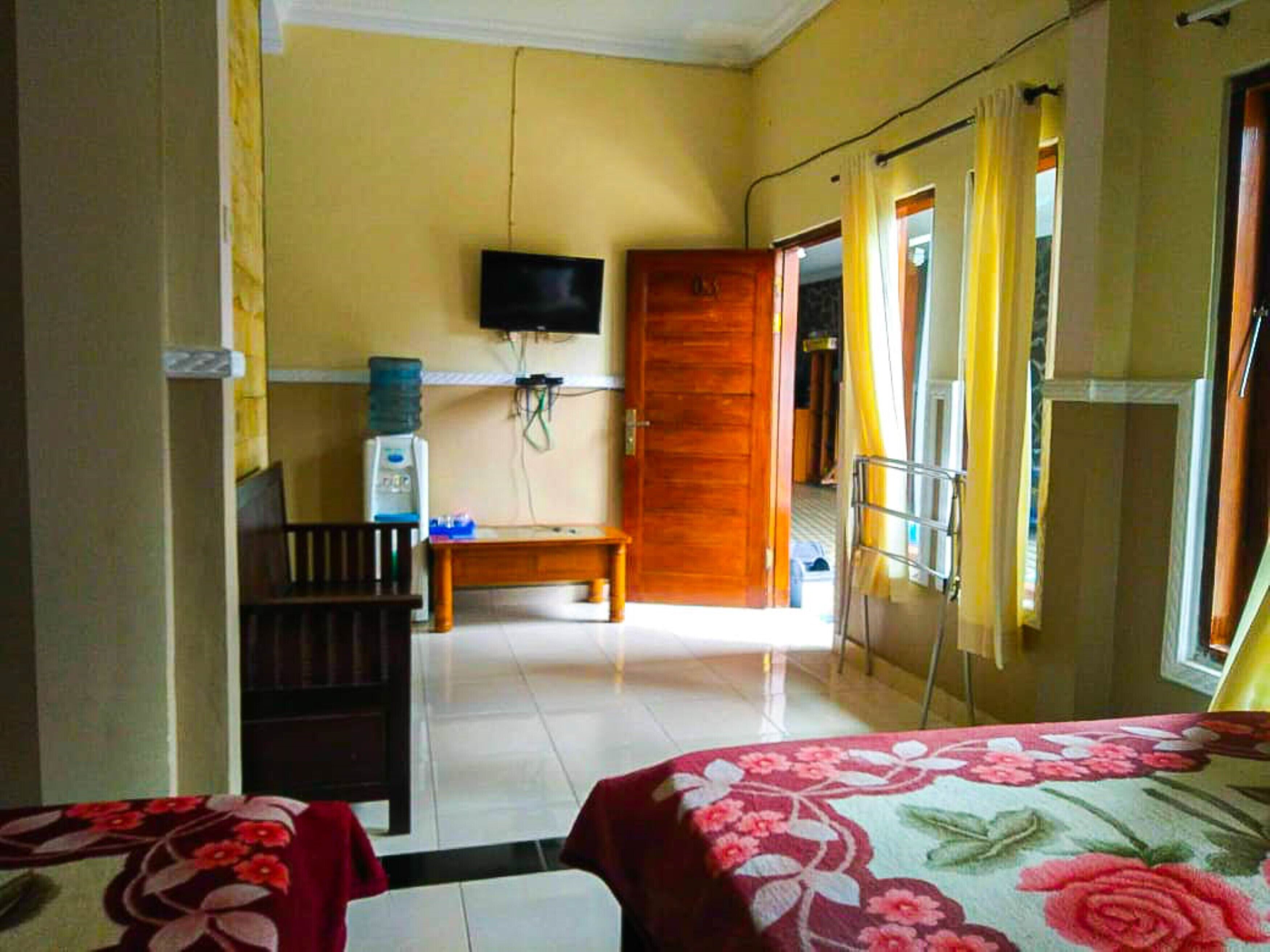 A hotel room with a bed, a desk, a television, and a water dispenser.