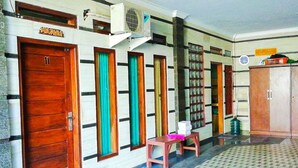 A hallway with wooden doors, colorful curtains, and a tiled floor. - Hotel Abad Baru 1 (Pangandaran)