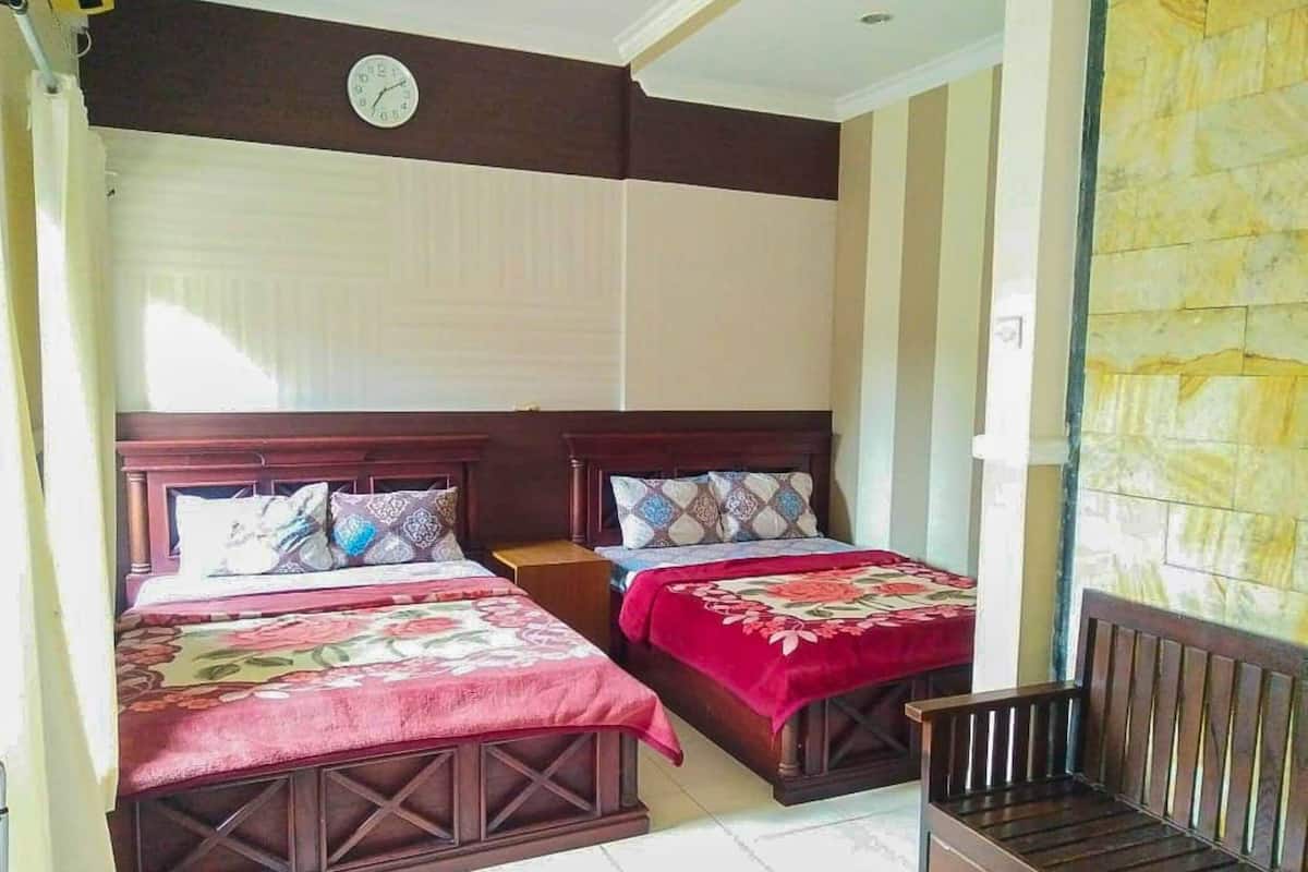 Habitación de hotel con dos camas de madera, un banco de madera, un reloj en la pared y una pared de piedra.