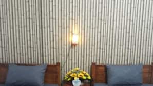 Una habitación con dos camas, una mesita con un florero y una pared con estampado de bambú.