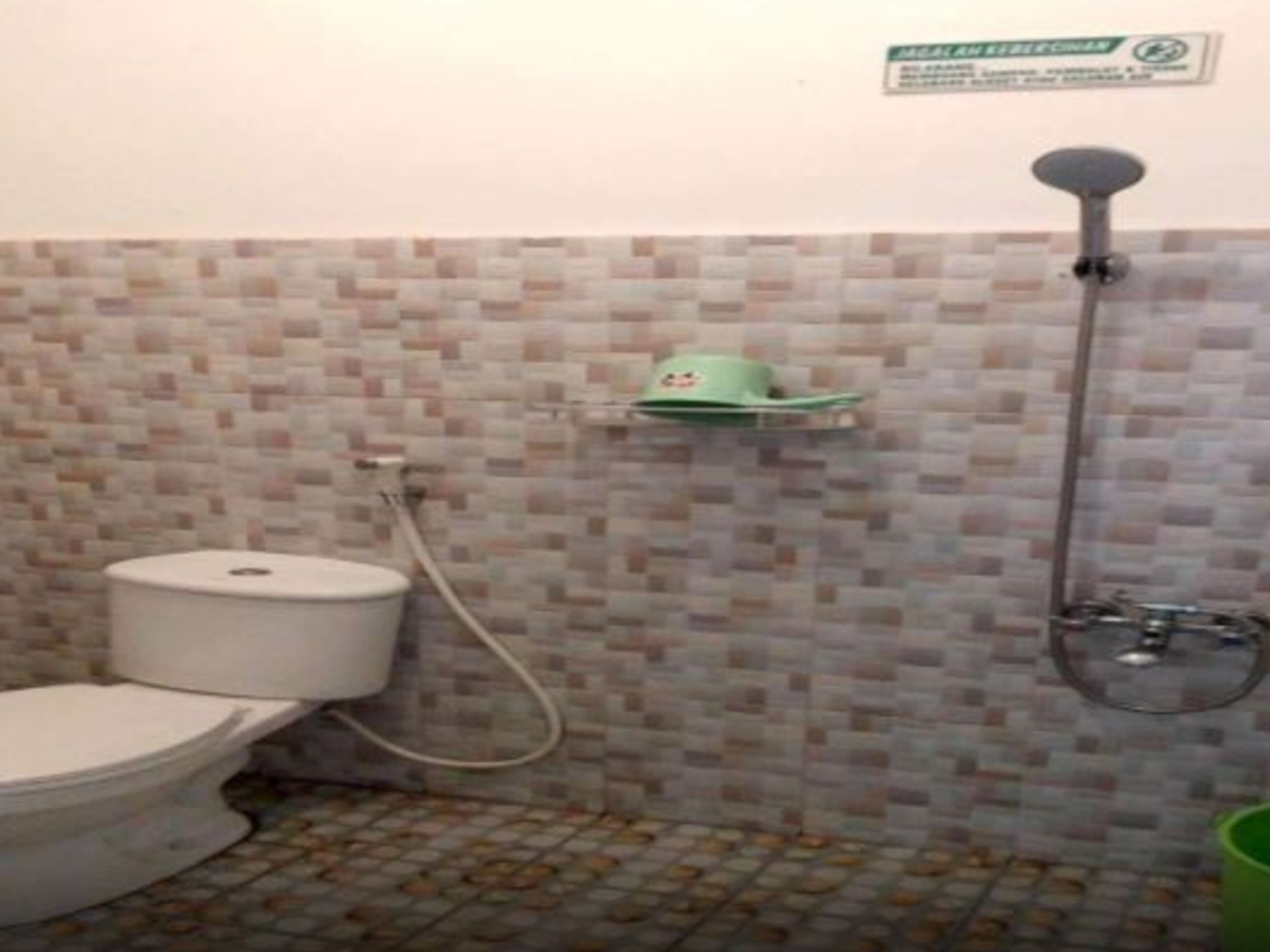 Une salle de bain avec des toilettes, une douche et un mur carrelé.