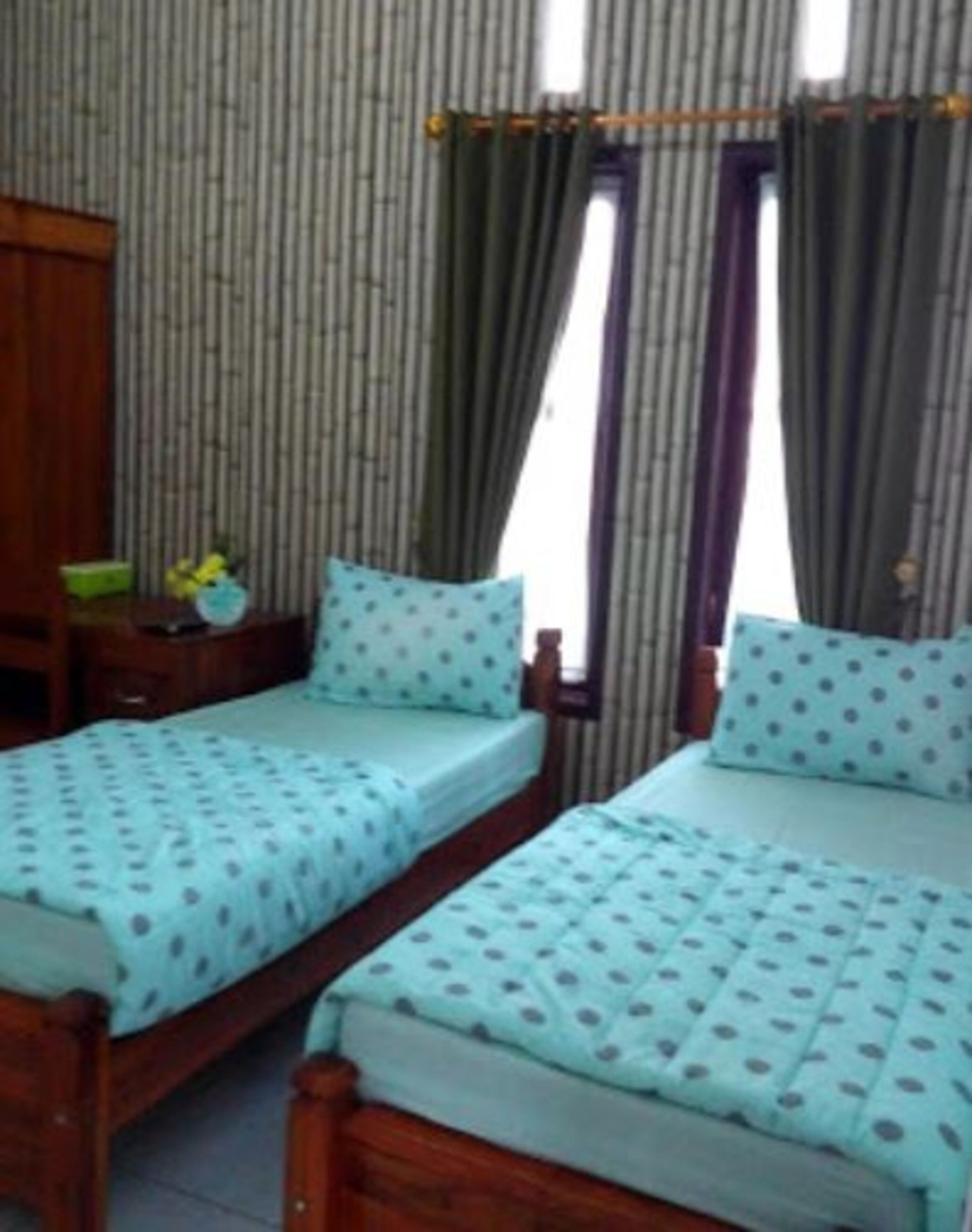 A room with two wooden beds, striped curtains, and a wooden wardrobe.