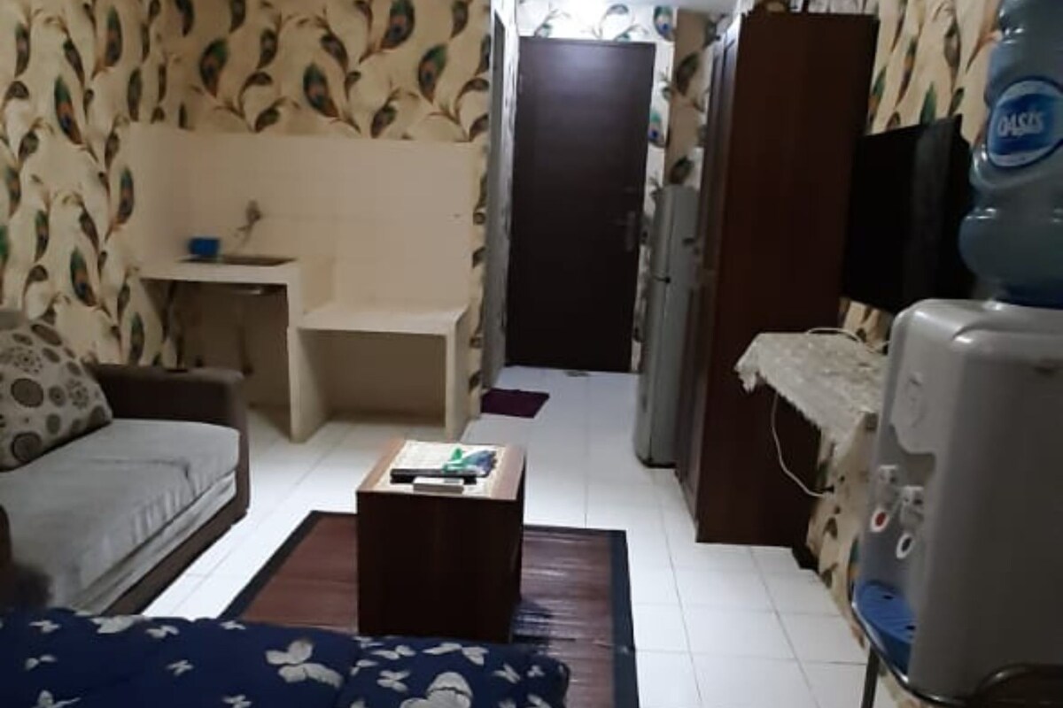 A room with a bed, a desk, a water dispenser, and a television.