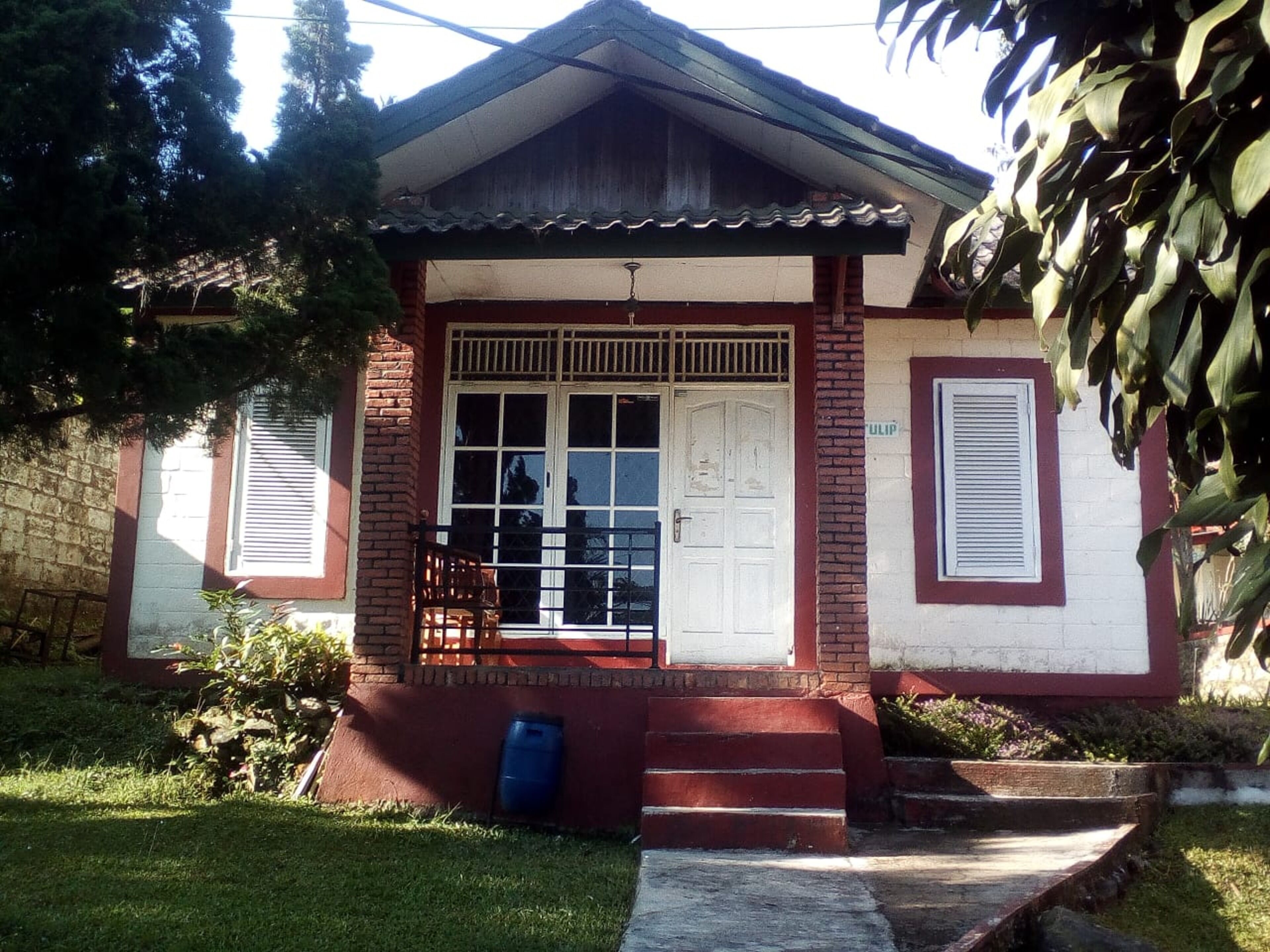 A small, single-story house with a front porch, a white door, and a small balcony.