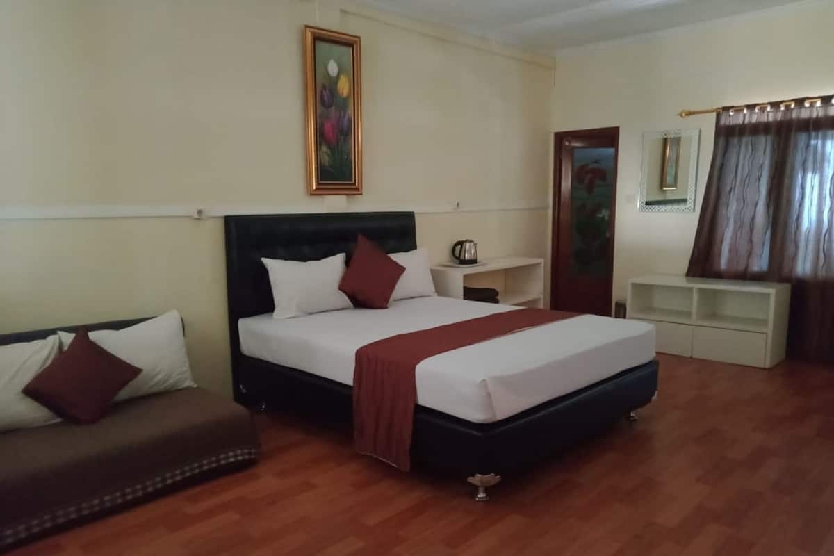 Una camera d'albergo con un letto, un divano, un comodino, uno specchio e un quadro appeso al muro.