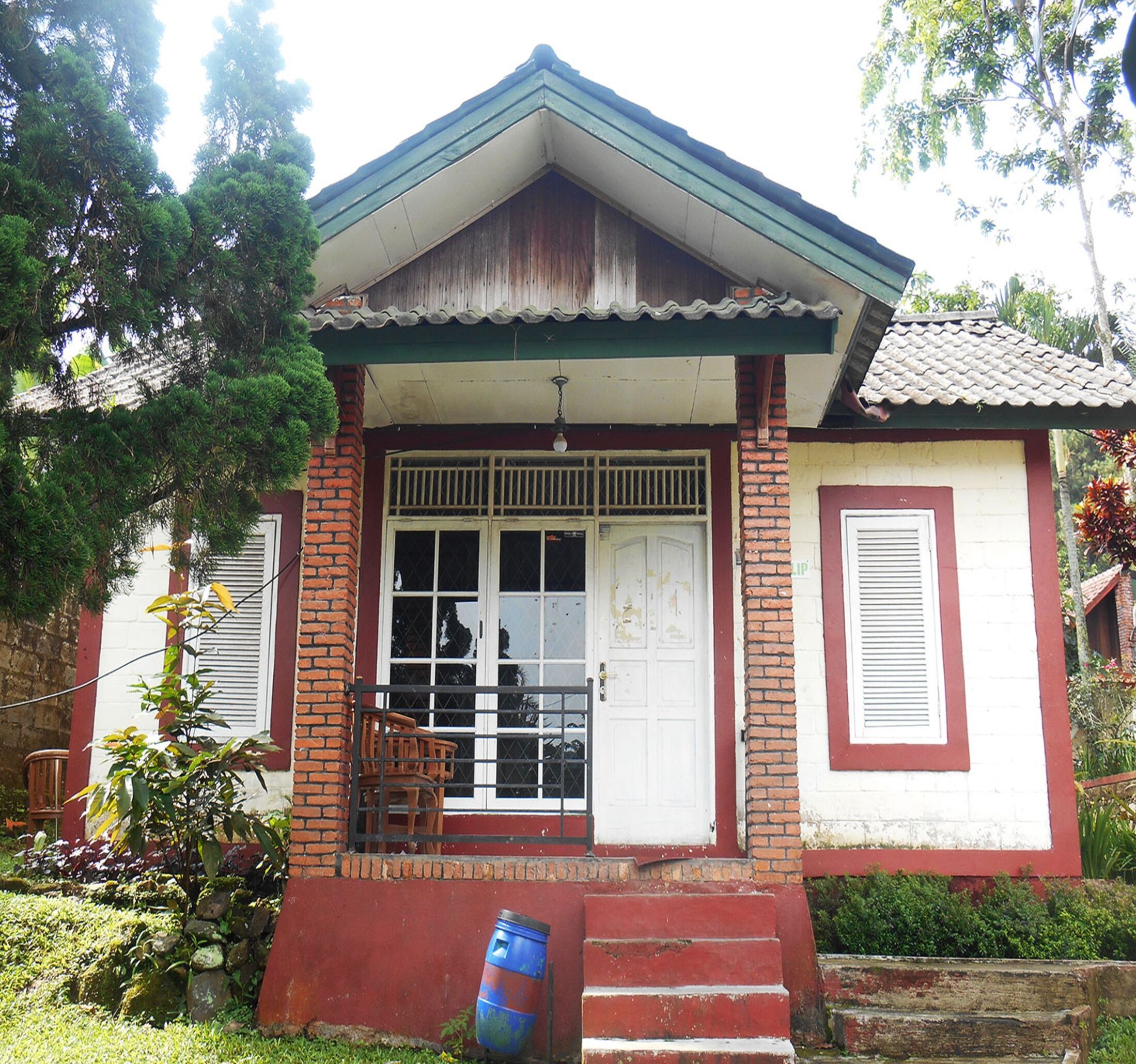 A small house with a porch, a single door, and a window with bars.