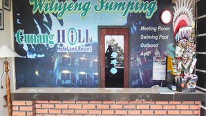 Een receptiebalie bij Wiryeng Pumping Cunang Hill Hotel and Resort, met een bord waarop faciliteiten staan vermeld zoals een vergaderzaal, zwembad en een restaurant.