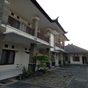 A multi-story residential building with balconies, a tiled courtyard, and some greenery. - Pondok Wisata Intan Indah 1 (Denpasar)