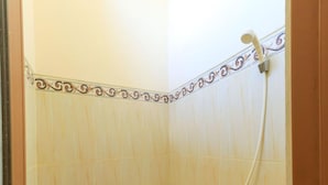 A small bathroom with a toilet, a shower, and a hand dryer. - Pondok Wisata Intan Indah 1 (Denpasar)