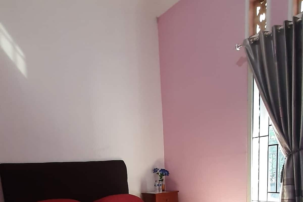 Ein Schlafzimmer mit Bett, Nachttisch und einem Fenster mit Vorhängen.