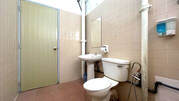 A small bathroom with a toilet, sink, and shower.