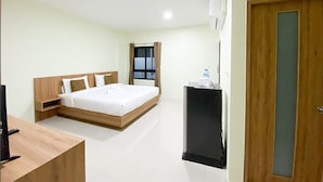 A hotel room with a wooden bed, a desk, a TV, and a water dispenser. - PP Residence Phuket (Sa Khu)