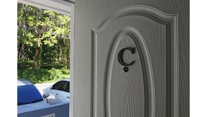 A door with a carved 'C' and a circular handle, set in a textured wall. - PP Residence Phuket (Sa Khu)