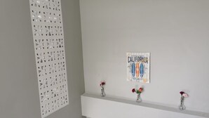 A wall with a decorative panel, a framed poster, and two vases with flowers. - PP Residence Phuket (Sa Khu)