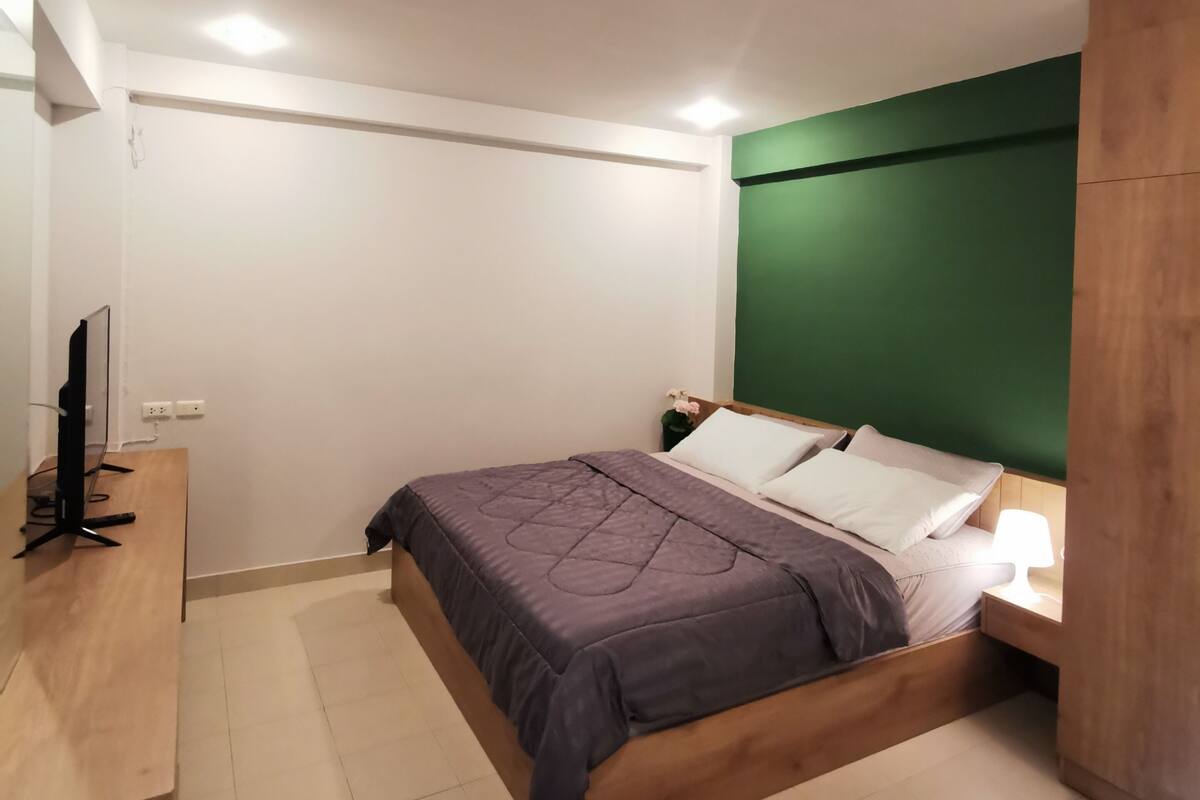 A bedroom with a bed, bedside table, and a desk with a computer.