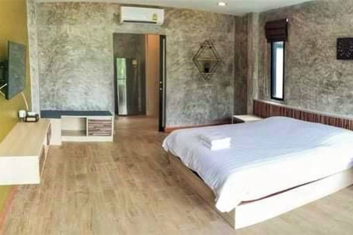 A bedroom with a large bed, a bedside table, a wall-mounted TV, and a window with curtains.
