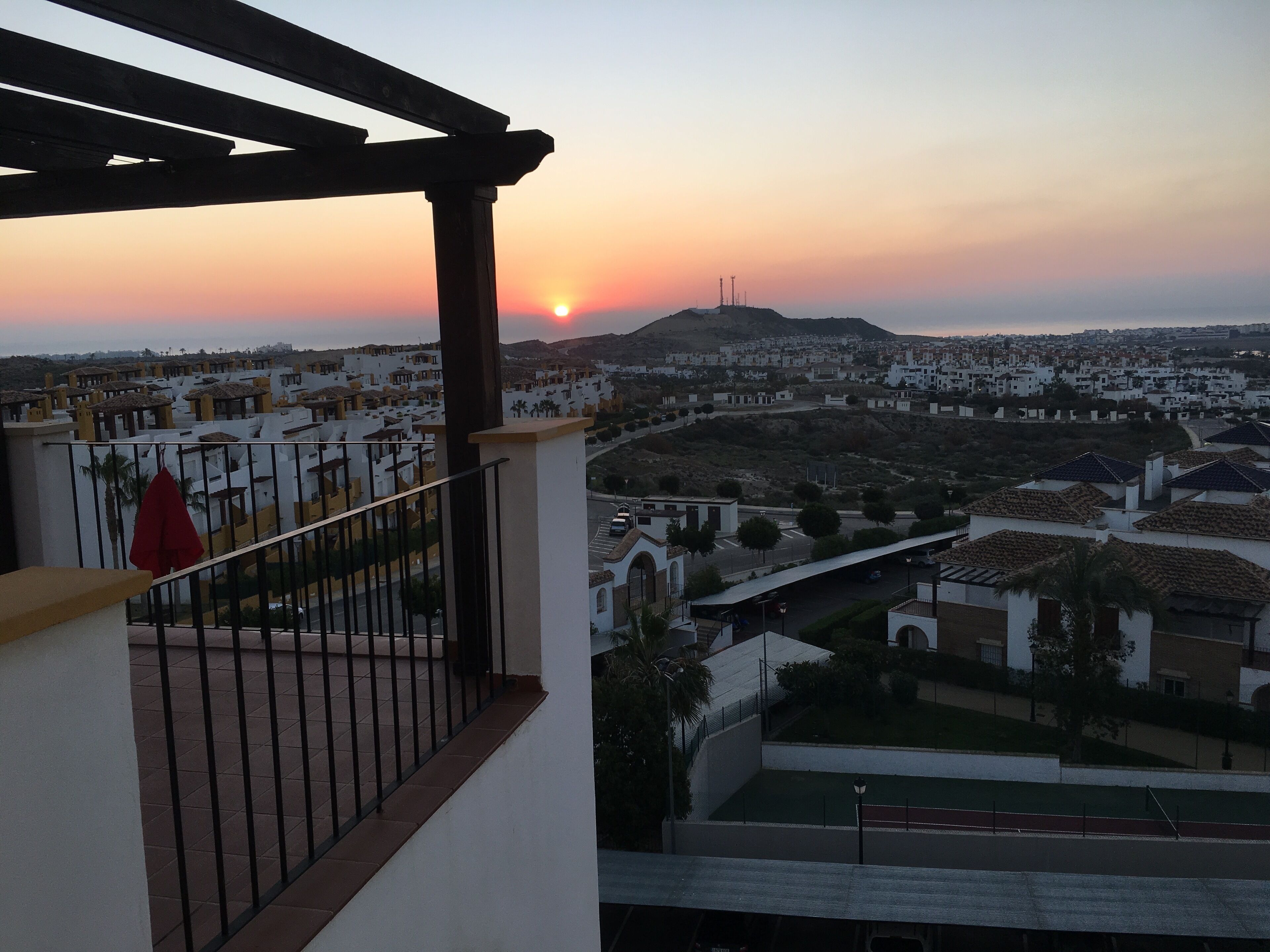 A balcony with a view of a residential area during sunset.