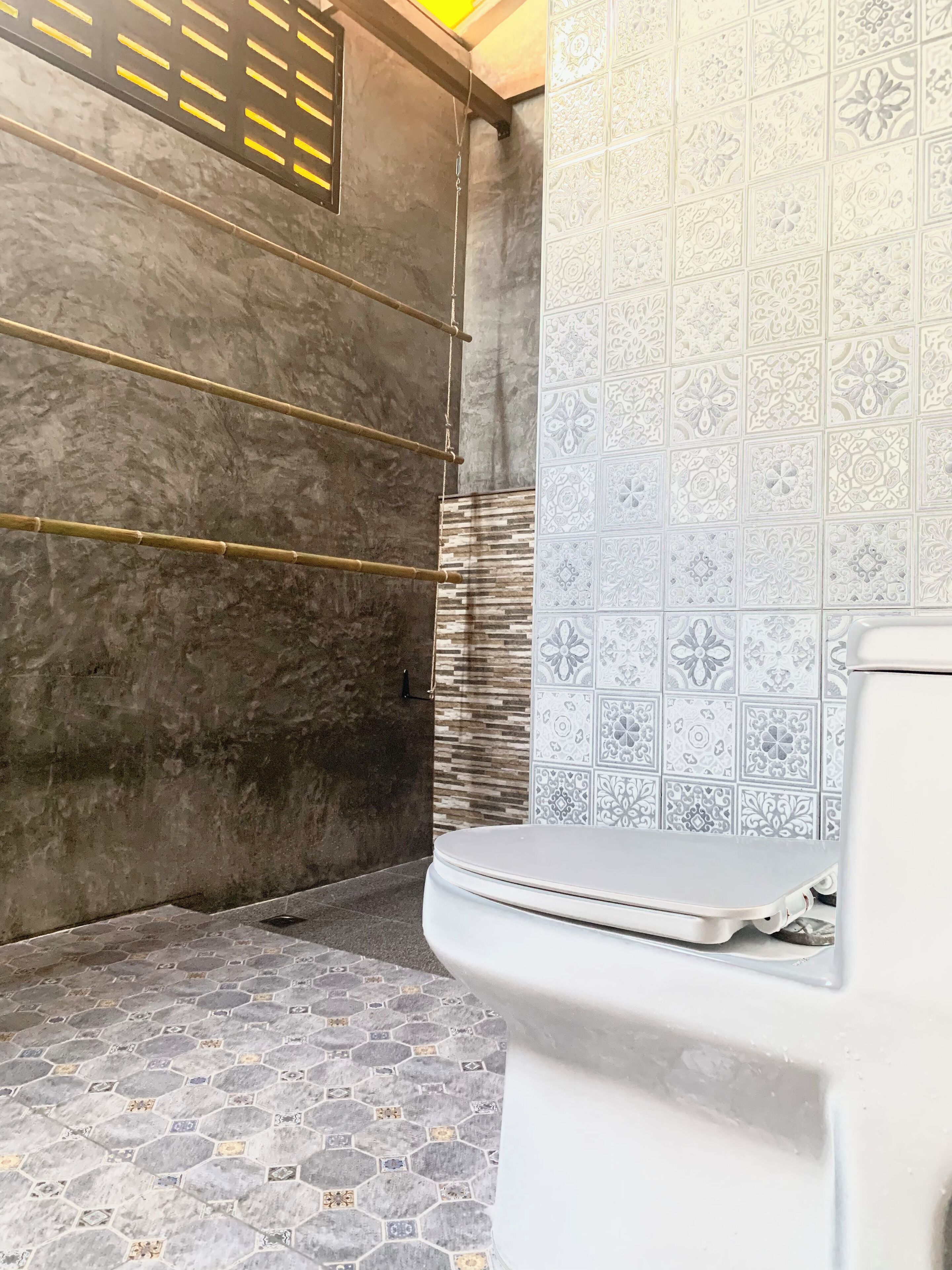 A bathroom with a toilet, a shower area with a tiled wall, and a bamboo shelf.